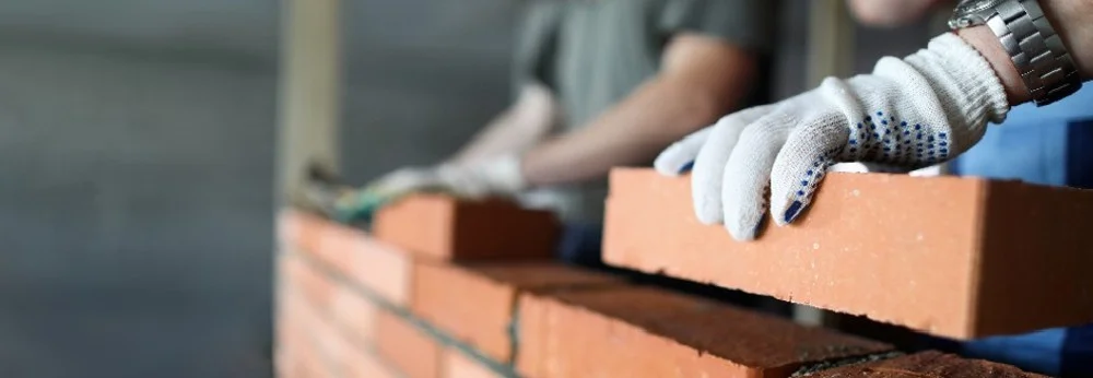 Person mauert Ziegelsteine